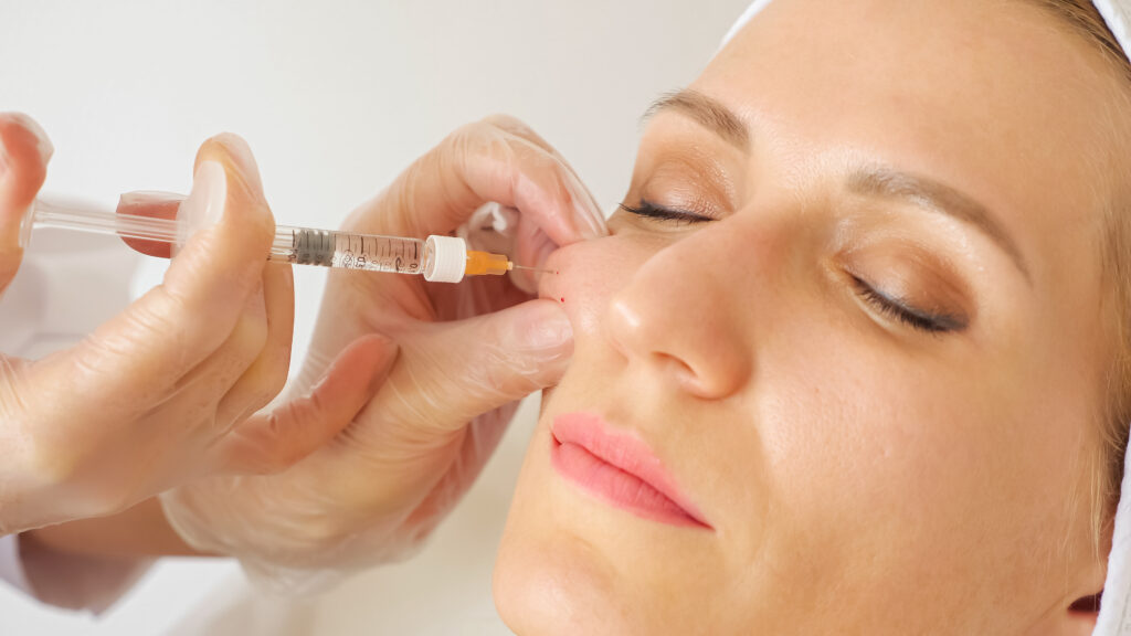 close up beautician giving injection into cheek woman
